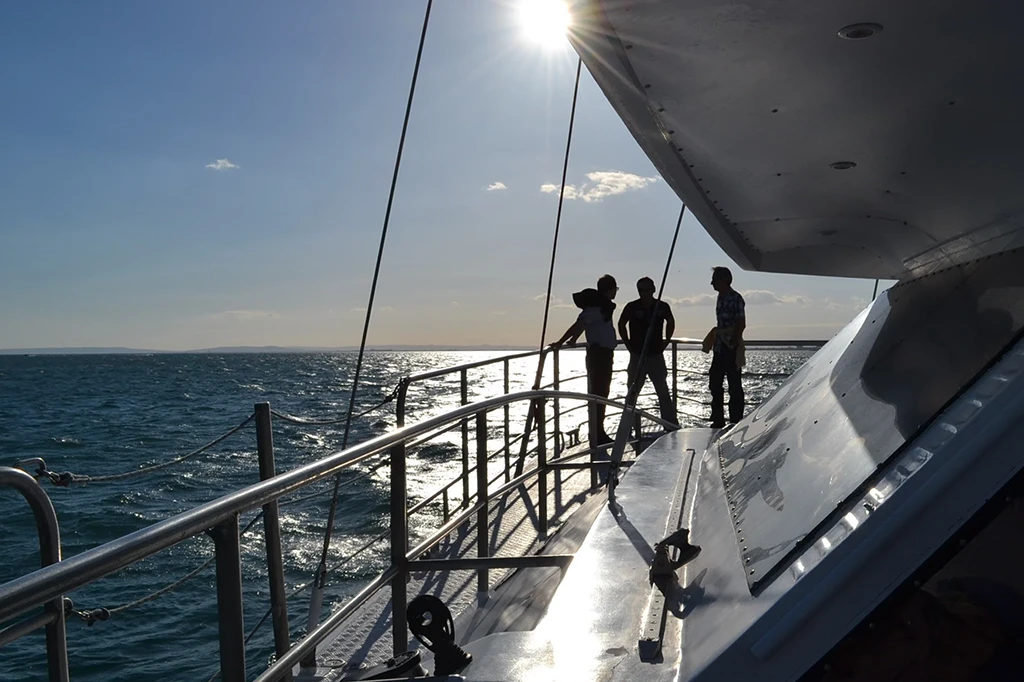 3 personnes se tenant debout sur un catamaran