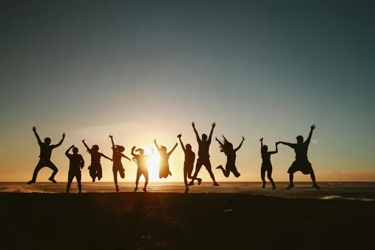 Groupe de gens sautant devant un couché de soleil